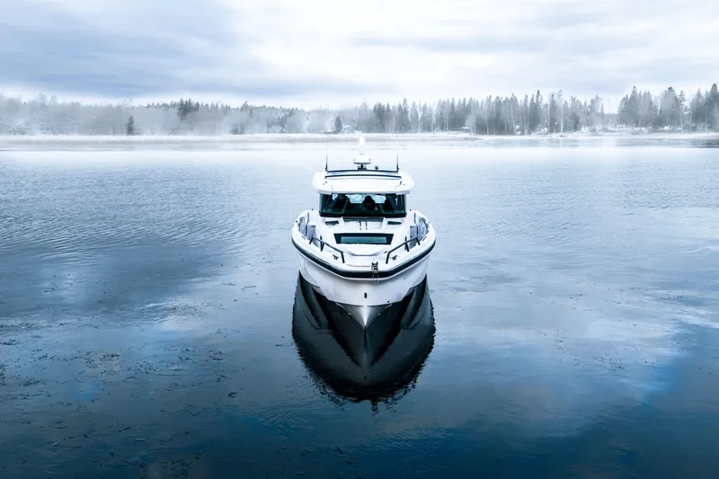 Slide: The Image of 2026 Axopar 38 Cross Cabin boat on a serene, misty lake. - 8