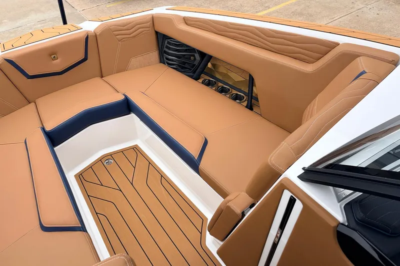 Slide: The Image of 2026 Nautique Super Air Nautique G25 interior with tan and navy seating, cup holders, and teak flooring. - 19