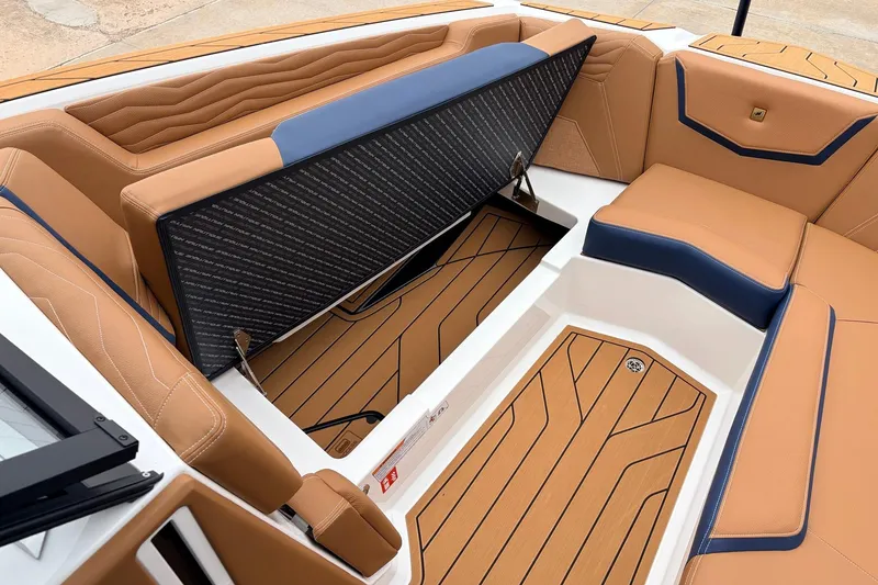 Slide: The Image of 2026 Nautique Super Air Nautique G25 interior with tan and blue seating, open storage compartment. - 24