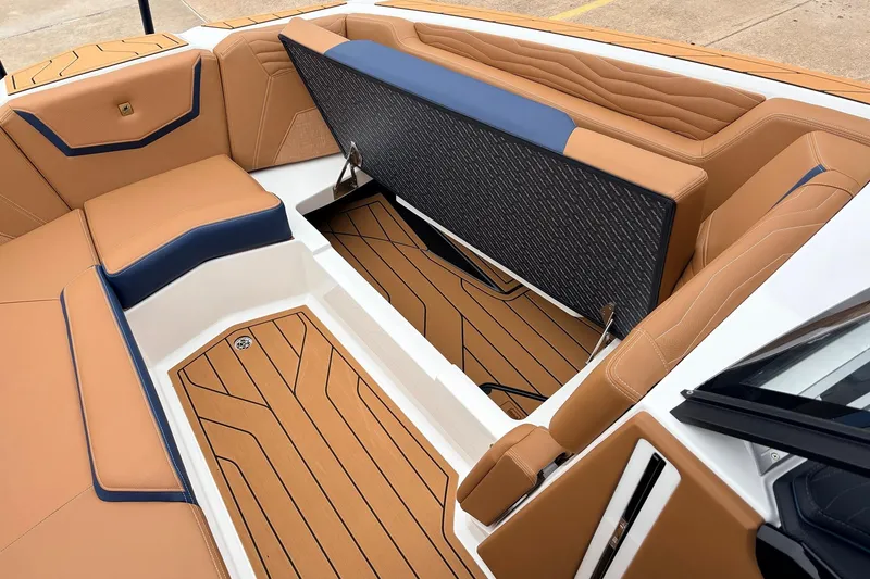 Slide: The Image of 2026 Nautique Super Air Nautique G25 interior with tan and blue seating, open storage compartment. - 25