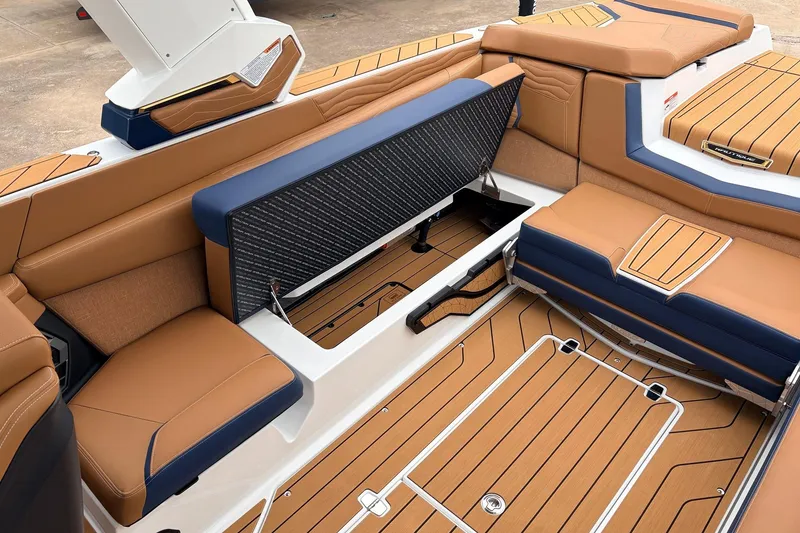 Slide: The Image of 2026 Nautique Super Air Nautique G25 interior with tan and blue seating, open storage compartment. - 50