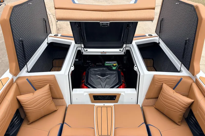 Slide: The Image of 2026 Nautique Super Air Nautique G25 boat interior with open engine compartment and tan seating. - 62