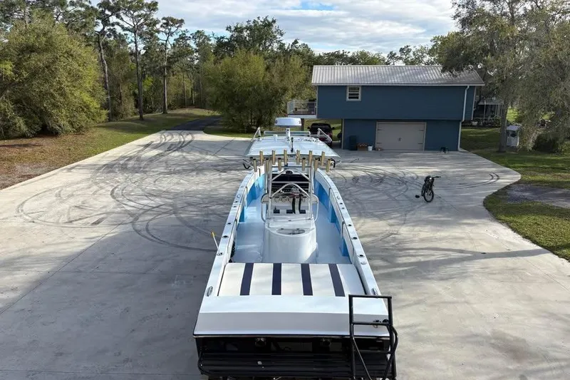 Slide: The Image of 2018 Catamaran Coaches Lightning Powerboats on driveway near blue house, surrounded by trees. - 12