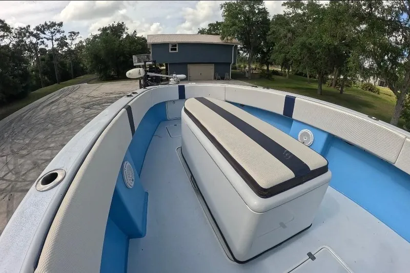 Slide: The Image of 2018 Catamaran Coaches 38 Lightning boat deck with cushioned seating, surrounded by trees and a house. - 30