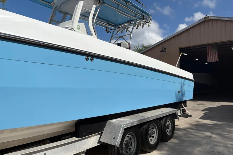 Slide: The Image of 2018 Catamaran Coaches 38 Lightning boat on trailer, blue and white exterior, near a garage. - 7