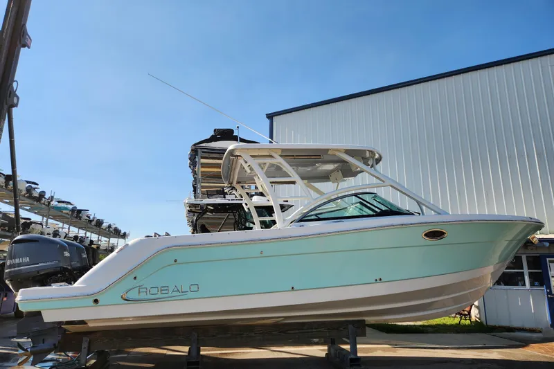 Slide: The Image of 2019 Robalo R317 Dual Console boat displayed outdoors on a sunny day. - 2