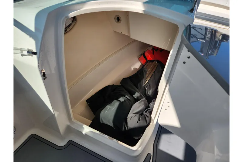 Slide: The Image of Storage compartment of a 2019 Robalo R317 Dual Console boat, containing life jackets and gear. - 23