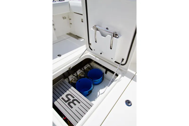 Slide: The Image of Open storage compartment on 2026 Regulator 35 boat, featuring organized interior with blue buckets. - 19