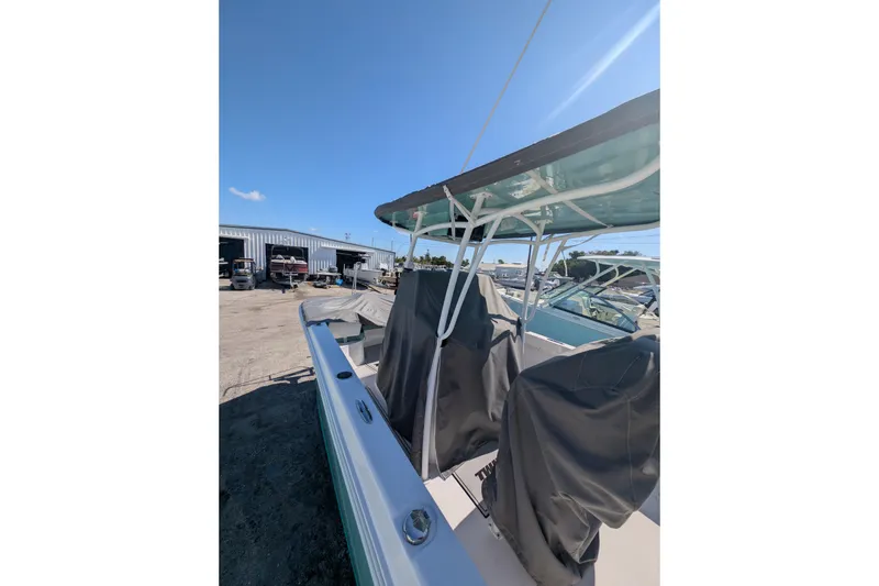 Slide: The Image of 2024 Twin Vee 240 GFX CC boat with covered seats, parked outdoors under clear sky. - 10