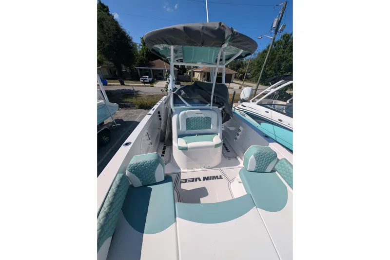 Slide: The Image of 2024 Twin Vee 240 GFX CC boat with teal and white seating, docked outdoors. - 4