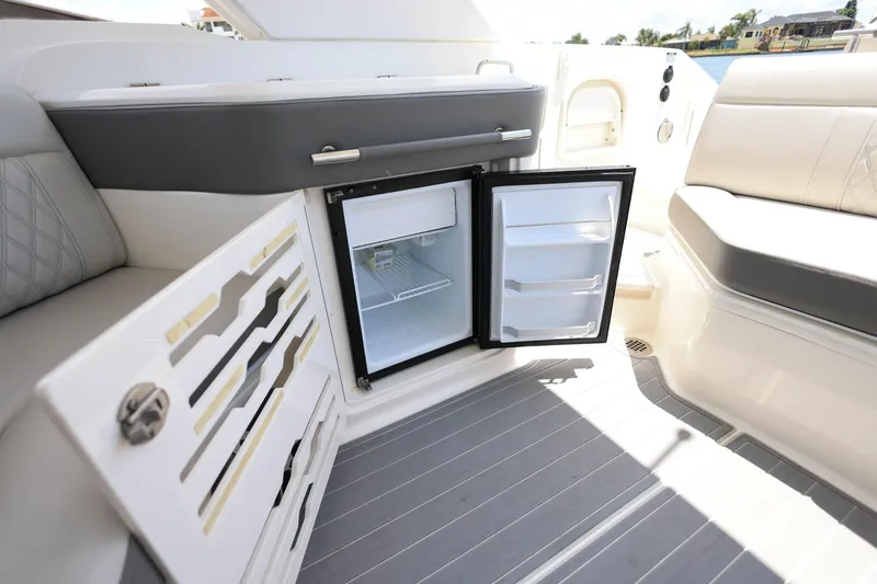 Slide: The Image of Interior of 2022 Sea Ray SLX 310 Outboard with open mini fridge and seating area. - 21
