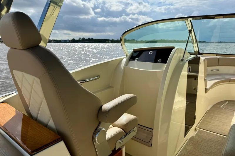 Slide: The Image of 2023 Chris-Craft Calypso 30 boat interior with helm seat and scenic water view. - 11
