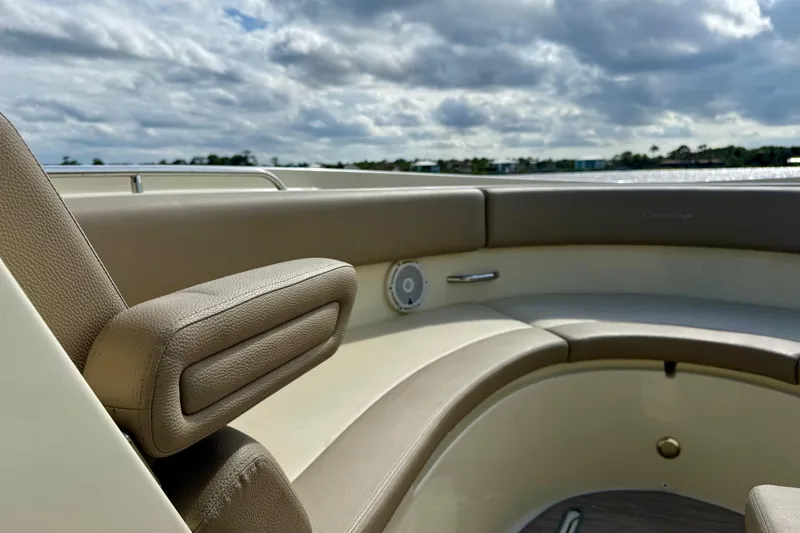 Slide: The Image of 2023 Chris-Craft Calypso 30 boat interior with beige seating and armrest under cloudy sky. - 18