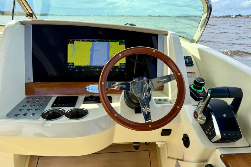 Slide: The Image of 2023 Chris-Craft Calypso 30 helm with navigation display and wooden steering wheel. - 5