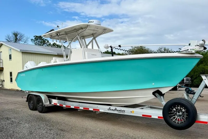 The Image of 2009 SeaHunter 29 Center Console boat on trailer, turquoise hull, parked outdoors. - 1