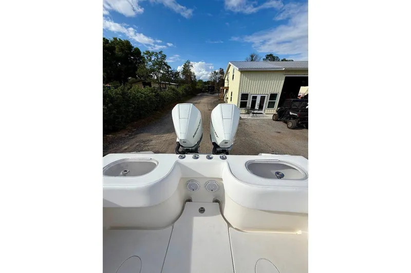 Slide: The Image of 2009 SeaHunter 29 Center Console boat with dual outboard motors, parked near a building. - 12