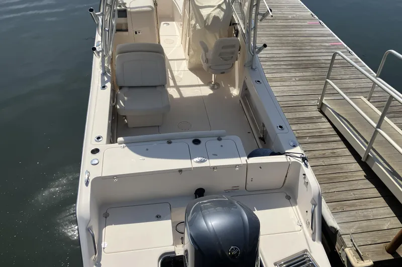 Slide: The Image of 2019 Grady-White Freedom 235 boat docked, showcasing spacious seating and sleek design. - 2