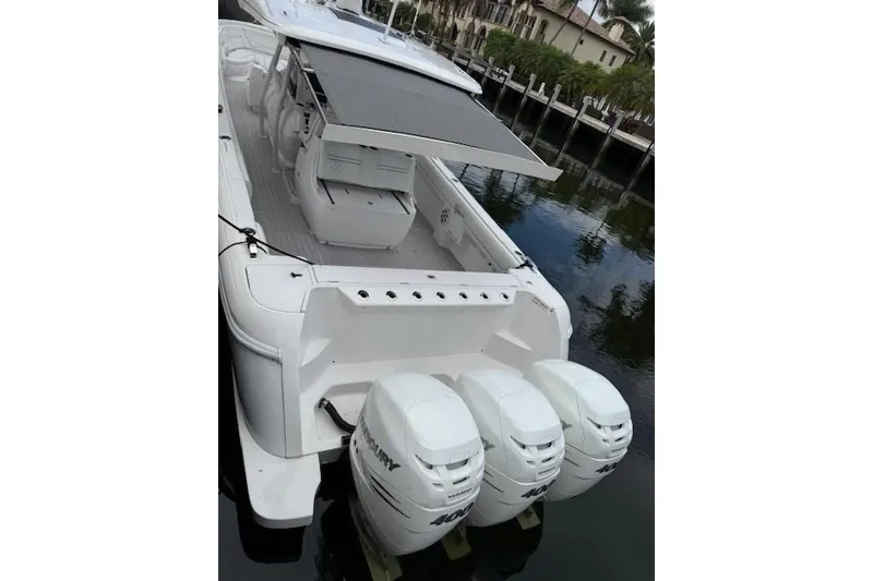 Slide: The Image of 2022 Intrepid 407 Nomad FE boat with triple outboard engines docked by waterfront homes. - 20