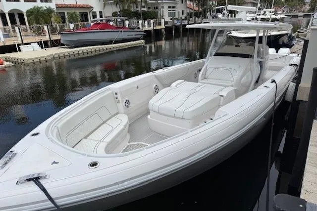 Slide: The Image of 2022 Intrepid 407 Nomad FE boat docked in a marina, showcasing sleek design and spacious seating. - 21