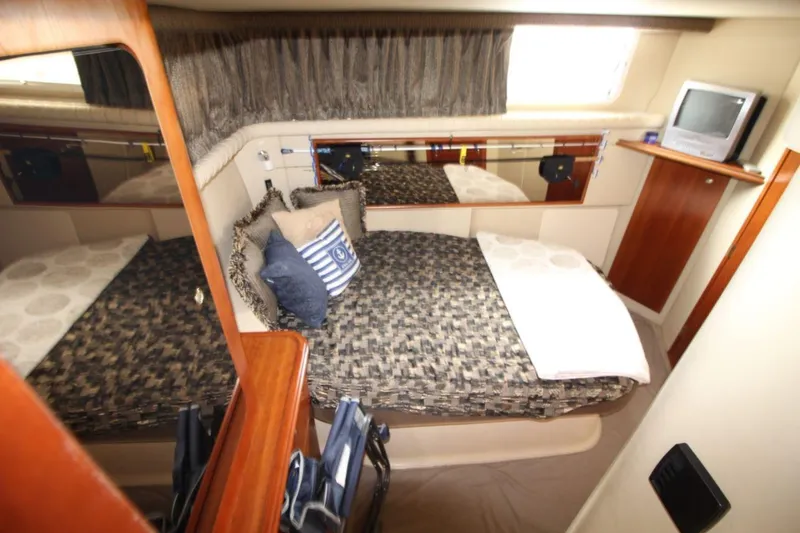 Slide: The Image of 2005 Cruisers Yachts 375 Motoryacht bedroom with patterned bedding and a small TV. - 26