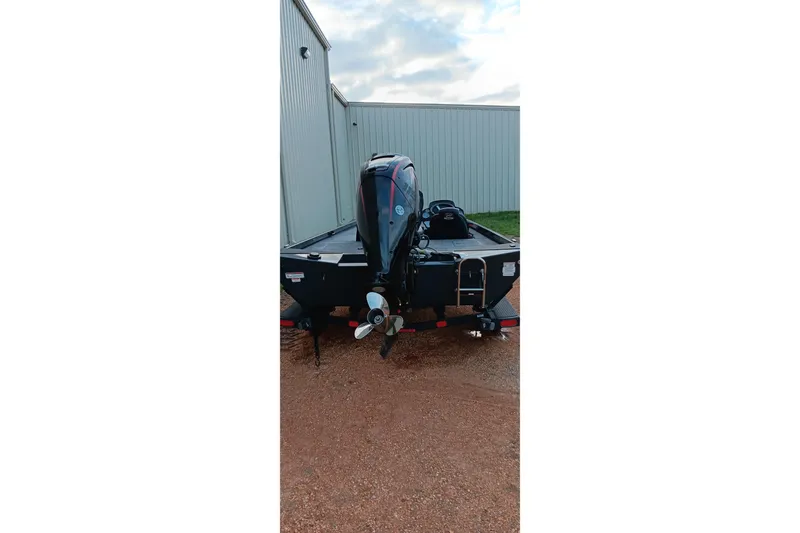 Slide: The Image of 2026 Ranger RT188C boat with outboard motor, parked on gravel near metal building. - 16