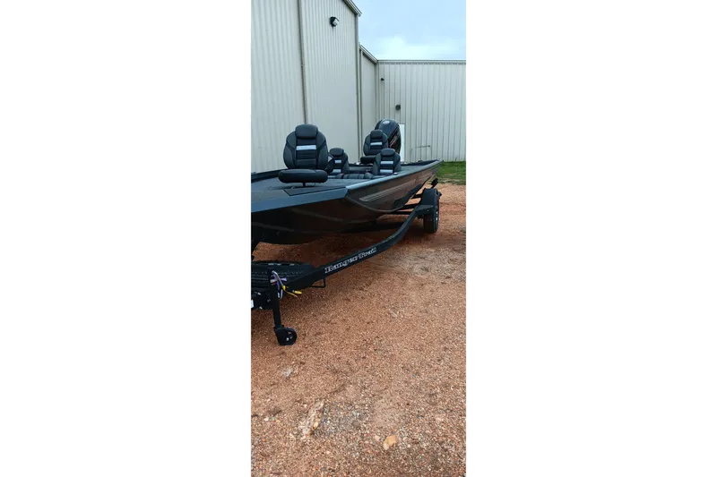 Slide: The Image of 2026 Ranger RT188C fishing boat on trailer, parked on gravel near metal building. - 6