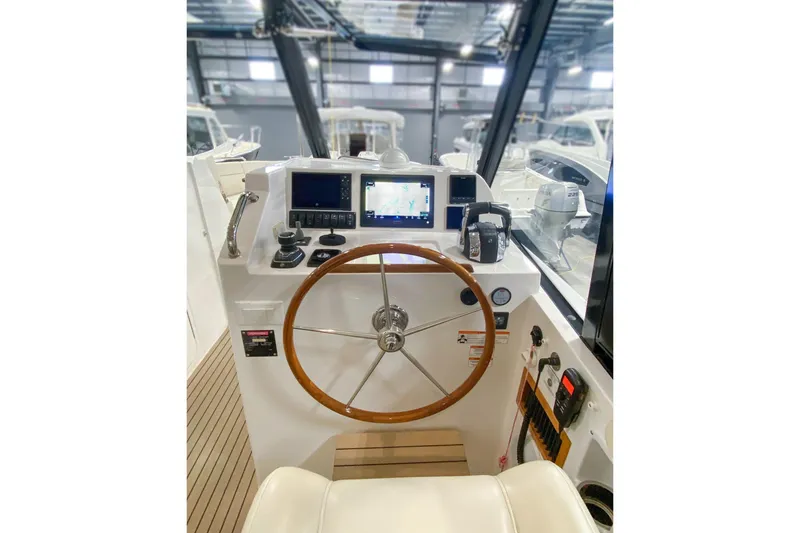 Slide: The Image of 2022 MJM 3 boat helm with wooden steering wheel and navigation screens. - 49