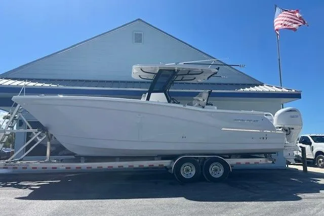 The Image of 2026 World Cat 280 CC-X boat on trailer, parked near building with American flag. - 1
