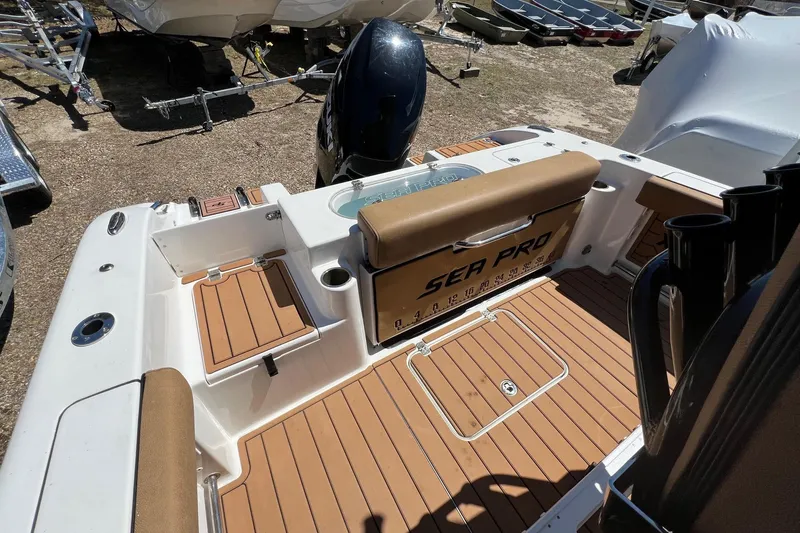 Slide: The Image of 2021 Sea Pro 239 Center Console boat interior with tan seating and wood-style flooring. - 5
