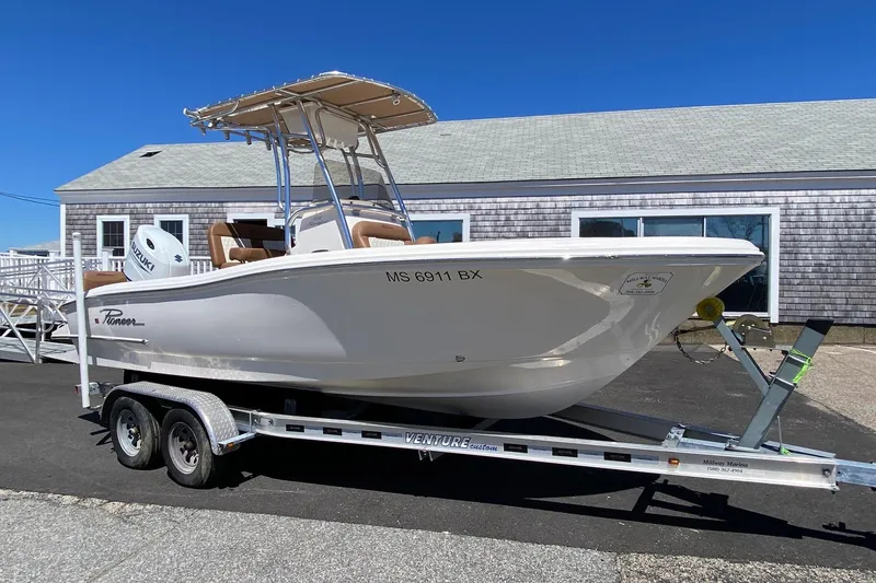 The Image of 2023 Pioneer 202 Sportfish boat on trailer, parked outside a building under clear blue sky. - 0