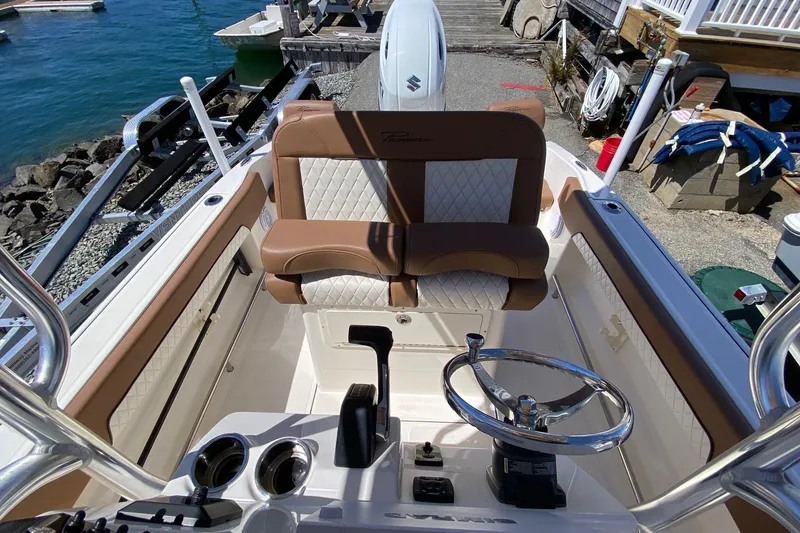 Slide: The Image of 2023 Pioneer 202 Sportfish boat interior with steering wheel and seating, dockside view. - 12