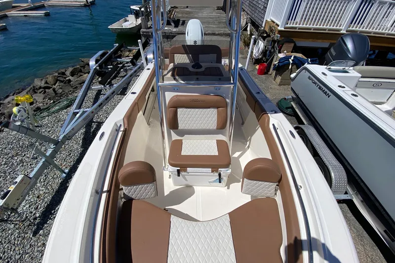 Slide: The Image of 2023 Pioneer 202 Sportfish boat interior with brown and white seating, docked by the water. - 16