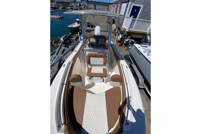 Slide: The Image of 2023 Pioneer 202 Sportfish boat with brown and white seating, docked near water. - 17