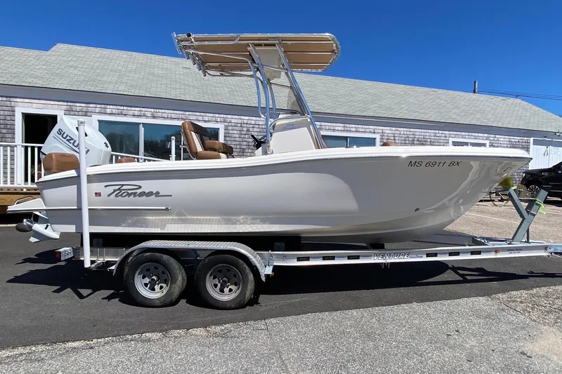 Slide: The Image of 2023 Pioneer 202 Sportfish boat on trailer, parked outdoors under clear blue sky. - 2