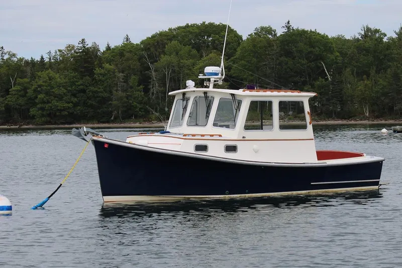 The Image of 1996 Webbers Cove 26 boat anchored on calm water with forested shoreline. - 0
