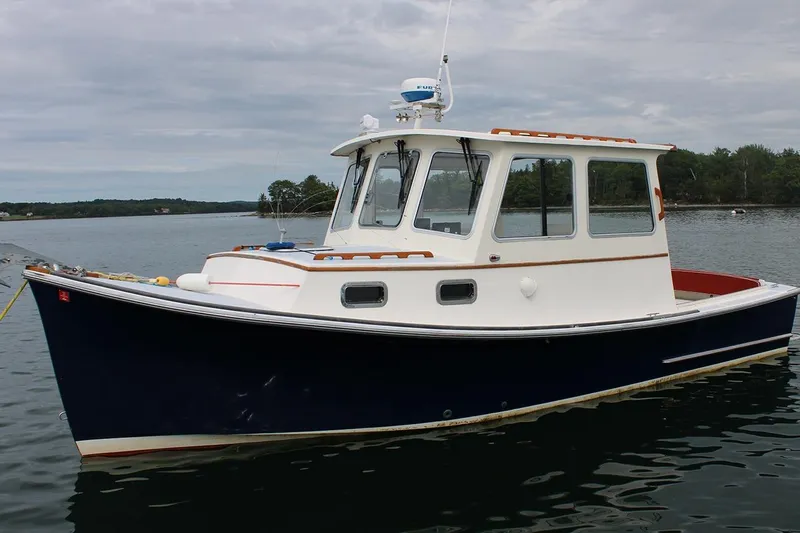Slide: The Image of 1996 Webbers Cove 26 boat on calm water, featuring a classic design and white cabin. - 3