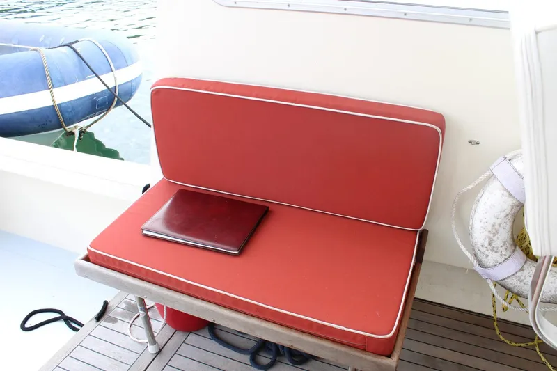 Slide: The Image of Red cushioned seat on 1996 Webbers Cove 26 boat with life preserver and docked dinghy. - 7
