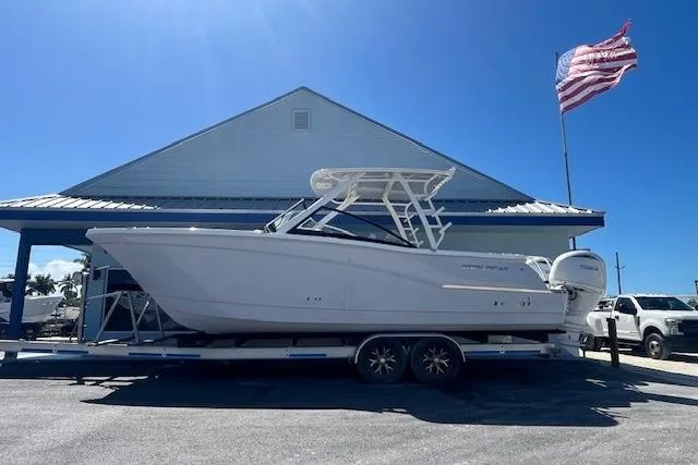 The Image of 2026 World Cat 280 DC-X boat on trailer, parked near building with American flag. - 1