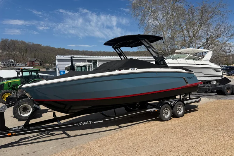 The Image of 2022 Cobalt R8 Surf boat on trailer, parked outdoors under clear blue sky. - 1