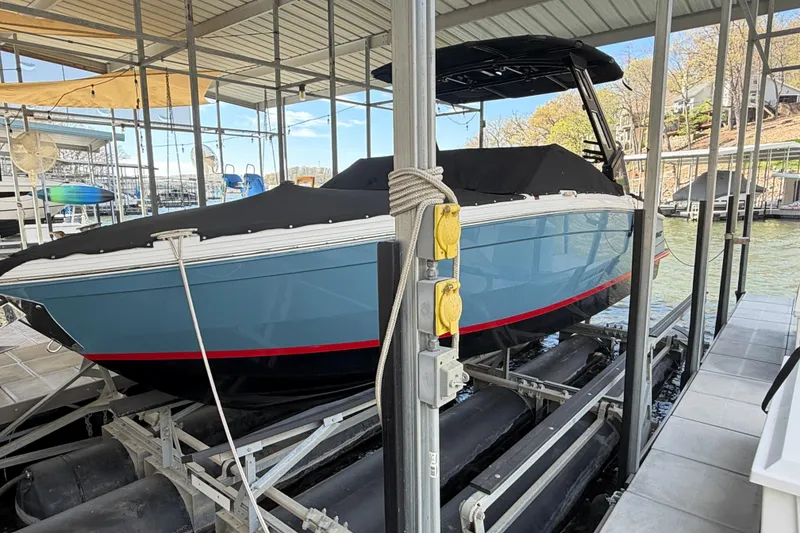 Slide: The Image of 2022 Cobalt R8 Surf boat docked, covered, and elevated in a marina setting. - 11