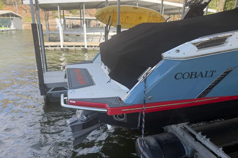 Slide: The Image of 2022 Cobalt R8 Surf boat docked, covered, with visible branding and surf platform. - 13