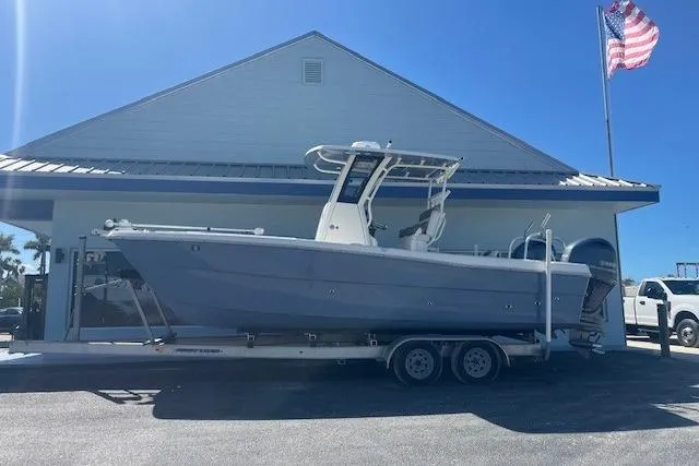 The Image of 2022 World Cat 235 CC boat on trailer, parked outside building with American flag. - 1