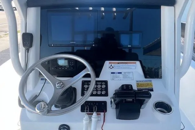 Slide: The Image of 2022 World Cat 235 CC boat dashboard with steering wheel, controls, and navigation screens. - 5