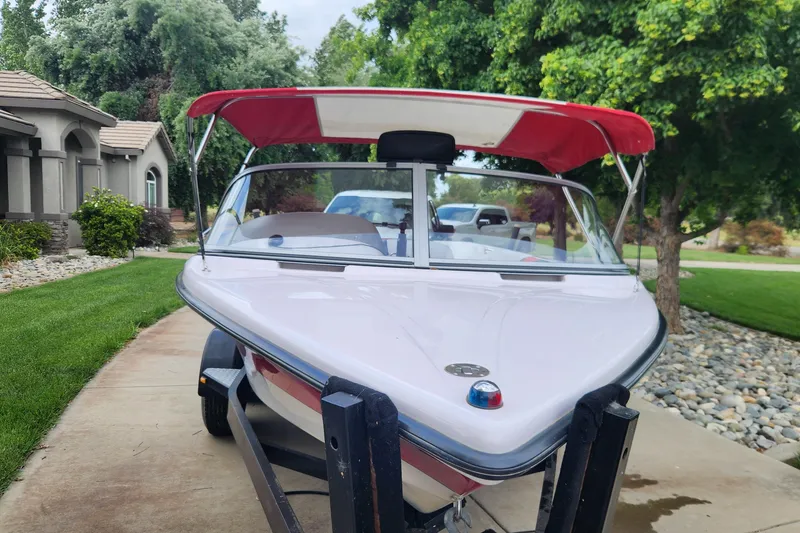 Slide: The Image of 2006 Correct Craft 196 boat with red canopy on driveway, surrounded by greenery. - 6