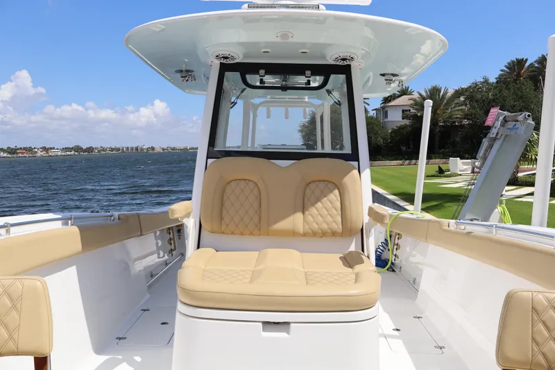 Slide: The Image of 2025 Sportsman Open 322 Center Console boat with tan seating, docked by a scenic waterfront. - 8
