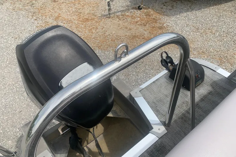 Slide: The Image of 2015 Avalon Windjammer Elite boat with motor and control panel, on gravel surface. - 14