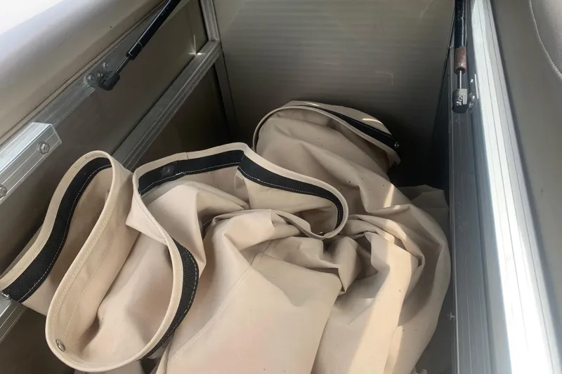 Slide: The Image of Storage compartment with beige canvas bags in a 2015 Avalon Windjammer Elite boat. - 23