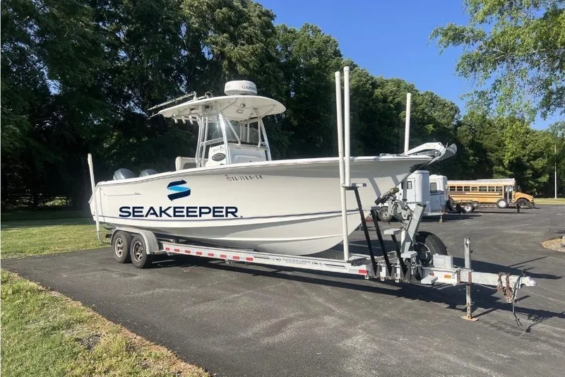 The Image of 2012 Sea Hunt Gamefish 27 boat on trailer, displayed outdoors under clear sky. - 0