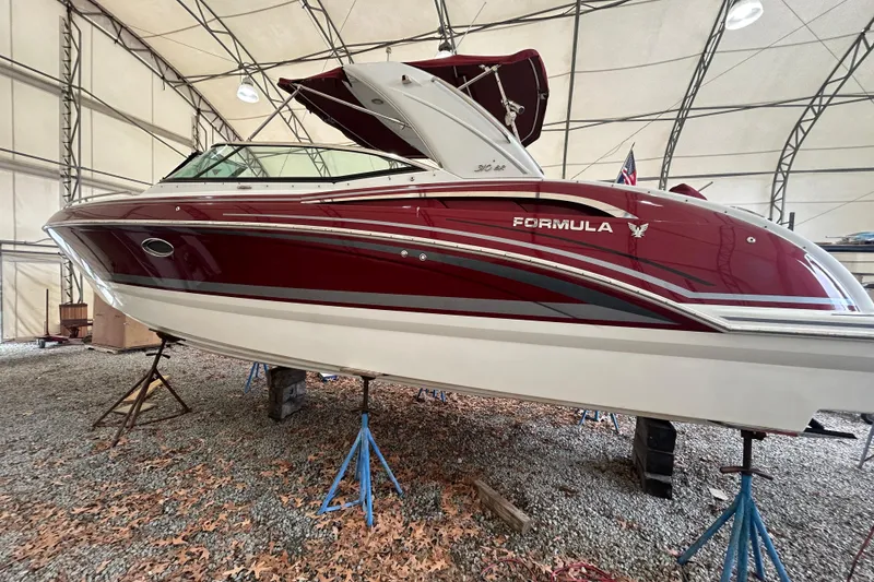 The Image of 2015 Formula 310 Bowrider in storage, red and white design, elevated on stands. - 1