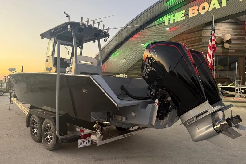 Slide: The Image of 2019 Metal Shark 28 CC boat on trailer, dual engines, parked near a building at sunset. - 7